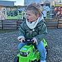 Charly participe au concours pour gagner de l'argent avec cette photo : toddler, child, toy_tractor, green_jacket, white_scarf, outdoor, gravel, wooden_crates, farm, market, banners, cow_image, fruit_image, blue_sky, curious_expression, casual_clothing, small_vehicle, playtime, daylight, young_boy