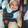 baby, infant, car_seat, harness, headwrap, white_clothing, smiling, drool, cute, child, seatbelt, safety, black_straps, red_button, portrait, indoors, closeup, face, chubby_cheeks, happy
