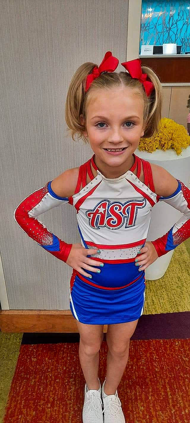 Kinley joined the competition — help win amazing prizes! blond, cheerleading, cheerleading_uniform, child, clothing, electric_blue, face, happy, human_leg, jersey, joy, person, player, red, sleeve, smile, sports_jersey, sports_uniform, sportswear, thigh