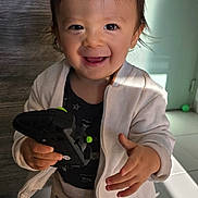 Lenny participe au concours pour gagner de l'argent avec cette photo : toddler, child, smiling, indoor, toy, controller, jacket, pants, happy, cute, person, face, hand, light, shadow, floor, door, green_toy, play, standing