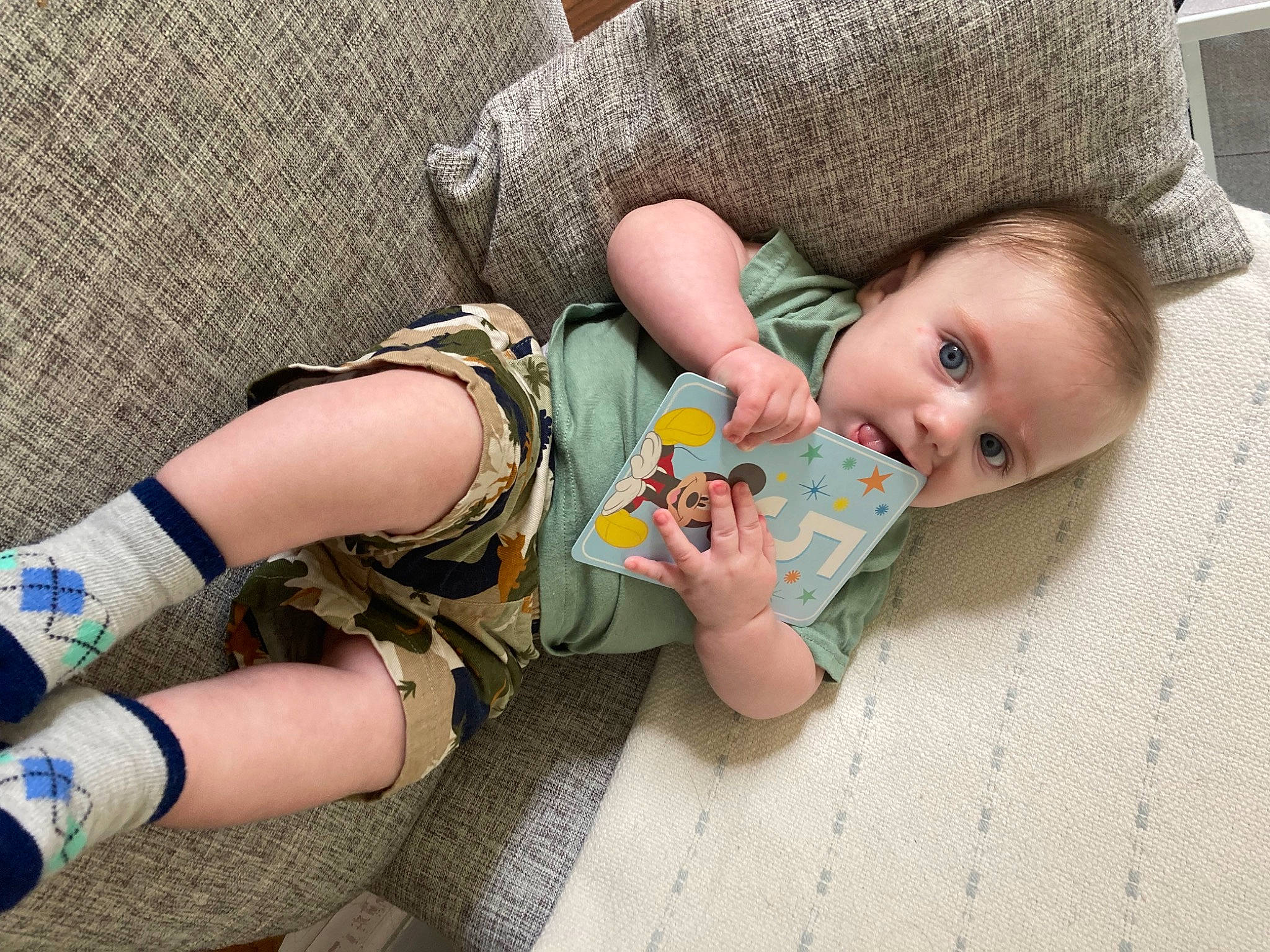 Everett is registered to the contest to win money with this photo: baby, baby_products, baby_toddler_clothing, comfort, doll, finger, flooring, grass, human_leg, joint, knee, leg, linens, nail, pattern, person, sitting, skin, surprise, thigh