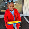 Tariyah is registered to the contest to win money with this photo: child, girl, red_coat, blue_hair_bows, toy, outdoor, porch, door, glass, car, house, smiling, white_shoes, tights, winter_clothing, curly_hair, playful, daylight, sidewalk, mat