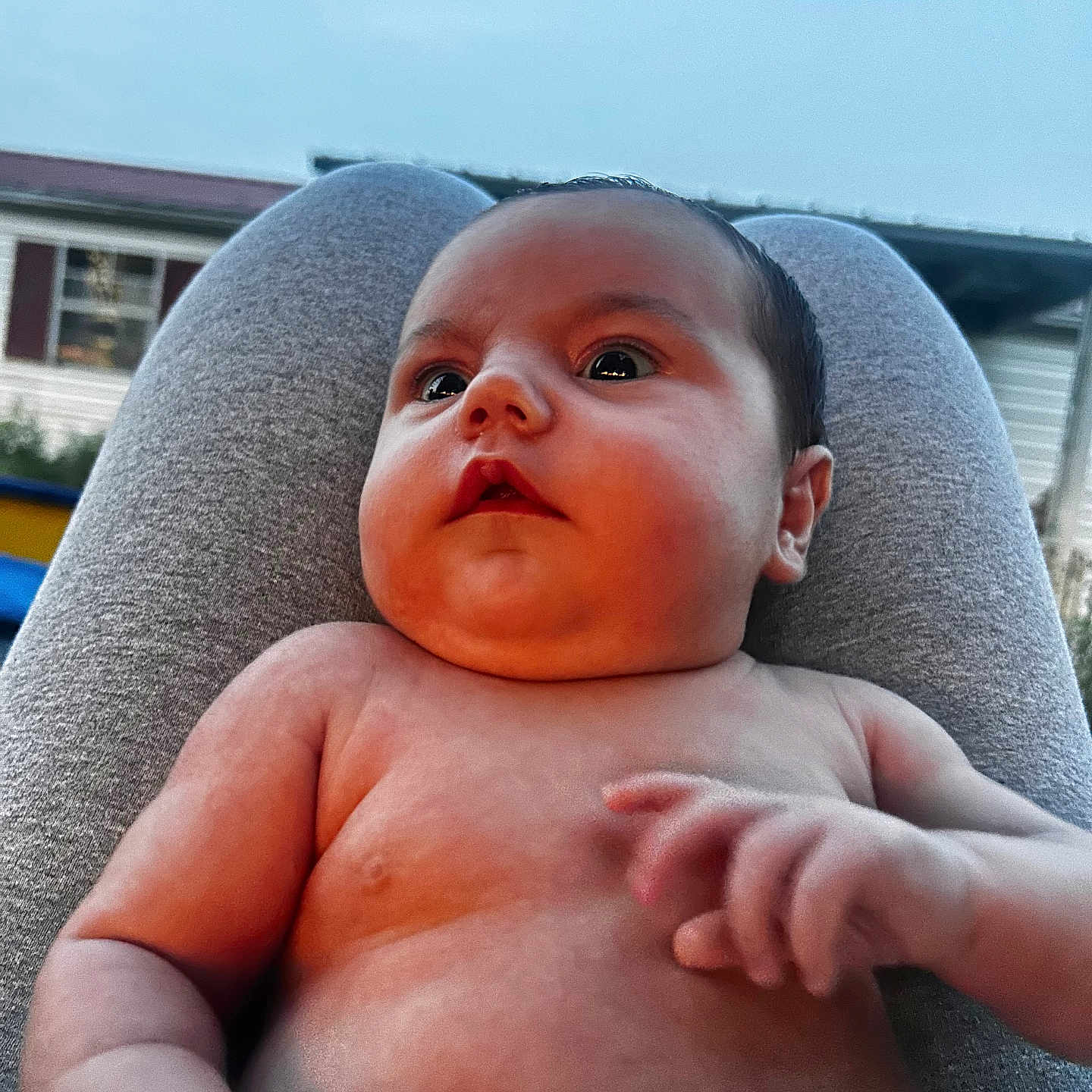 Lane is registered to the contest to win money with this photo: arm, baby, casual, child, closeup, curious, expression, eyes, face, hand, human, infant, lap, natural_light, outdoor, person, relaxed, skin, sky, torso