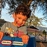 Aryan joined the competition — help win amazing prizes! blue, boy, child, curly_hair, daytime, fence, grass, happy, house, metal_chain, outdoor, park, playground, shadow, smiling, sunlight, swing, tree, tshirt, young
