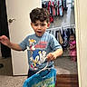 Aryan is registered to the contest to win money with this photo: bag, boy, carpet, child, closet, clothing, curly_hair, door, expression, furniture, girl, hanger, indoor, motion, person, room, shirt, socks, toddler, toy