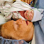 Journie joined the competition — help win amazing prizes! newborn, baby, mother, hospital, medical, blanket, oxygen_tube, striped_hat, surgical_cap, gown, skin, face, hand, healthcare, patient, bed, closeup, family, resting, intimate