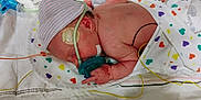 Journie is registered to the contest to win money with this photo: newborn, baby, hospital, incubator, medical_tubes, blanket, striped_hat, monitoring_wires, pacifier, infant, healthcare, bed, sleeping, skin, person, cute, small, lying_down, neonatal, care