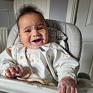 Elijah is registered to the contest to win money with this photo: baby, infant, high_chair, smiling, messy, food, bib, face_paint, happy, child, indoor, feeding, clothing, hand, tongue_out, person, cute, furniture, room, expression