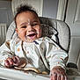 baby, infant, high_chair, smiling, messy, food, bib, face_paint, happy, child, indoor, feeding, clothing, hand, tongue_out, person, cute, furniture, room, expression