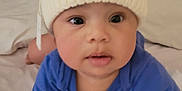 Elijah joined the competition — help win amazing prizes! baby, child, hat, knit_hat, blue_clothing, crawling, bed, blanket, indoors, person, cute, face, hands, sleepwear, infant, young_child, cozy, soft, curious, expression