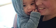 Elijah is registered to the contest to win money with this photo: baby, adult, hoodie, smiling, indoor, bed, blanket, person, cute, child, face, wearing, holding, cozy, happy, portrait, fuzzy, parent, toddler, home