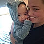 baby, adult, hoodie, smiling, indoor, bed, blanket, person, cute, child, face, wearing, holding, cozy, happy, portrait, fuzzy, parent, toddler, home