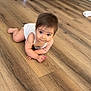 baby, infant, child, floor, wooden_floor, crawling, white_onesie, sofa, toy, home_interior, curious, smiling, person, indoors, cute, small_object, furniture, living_room, happy, young_child