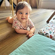 Louise a rejoint le concours — aidez-le/la à gagner de superbes lots ! baby, child, infant, floor, wooden_floor, onesie, floral_pattern, play_mat, indoors, natural_light, smiling, happy, cute, person, young_child, toddler, bright_eyes, crawling, home, soft_lighting
