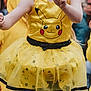 Kessy Noel a rejoint le concours — aidez-le/la à gagner de superbes lots ! child, costume, yellow, pikachu, glasses, face_paint, dress, tutu, black_tights, outdoor, people, performance, festival, crowd, fun, celebration, portrait, smile, headband, party