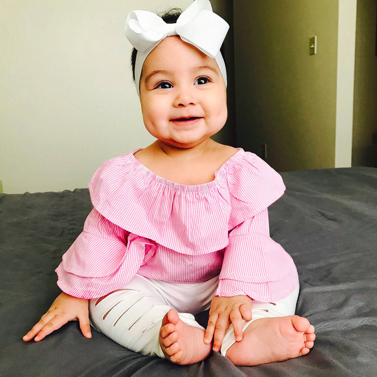 Athena is registered to the contest to win money with this photo: arm, baby, baby_toddler_clothing, cheek, child, costume, ear, gesture, hair_accessory, hand, happy, head, headband, headgear, person, pink, sitting, skin, sleeve, smile