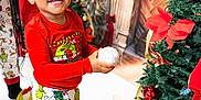A'Keloni Dior Davis is registered to the contest to win money with this photo: child, smiling, christmas_tree, ornament, present, pajamas, red_shirt, festive, holiday, fireplace_backdrop, decorations, gift_box, socks, indoor, happy, celebration, pinecone, ribbon, adult, portrait