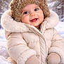 baby, child, winter_coat, fur_hat, mittens, snow, outdoors, smiling, rosy_cheeks, portrait, close_up, cozy, cold_weather, puffer_jacket, hood, cute, toddler, happy, nature, evergreen_trees