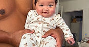 Kristyn is registered to the contest to win money with this photo: baby, child, person, adult, shirtless, indoor, bedroom, dog, animal, pajamas, floral_pattern, smiling, happy, hair, hands, face, furniture, doorway, blanket, skin