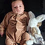 baby, infant, onesie, brown_clothing, stuffed_animal, bunny, soft_toy, lying_down, child, cute, indoors, portrait, young_child, cozy, sleepwear, plush, comfort, resting, adorable, face