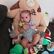 Télio a rejoint le concours — aidez-le/la à gagner de superbes lots ! baby, bright_colors, casual_clothing, child, colorful_toys, comfort, cushion, cute, happy, indoor, infant, pacifier, playtime, plush_toy, relaxing, smiling, sofa, soft_toy, stuffed_animal, teething_toy