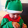 Télio participe au concours pour gagner de l'argent avec cette photo : toddler, child, green_hat, elf_costume, red_collar, indoor, couch, soft_light, focused, hands, holiday, festive, portrait, cute, young_child, sitting, face, clothing, buttoned_shirt, pom_pom