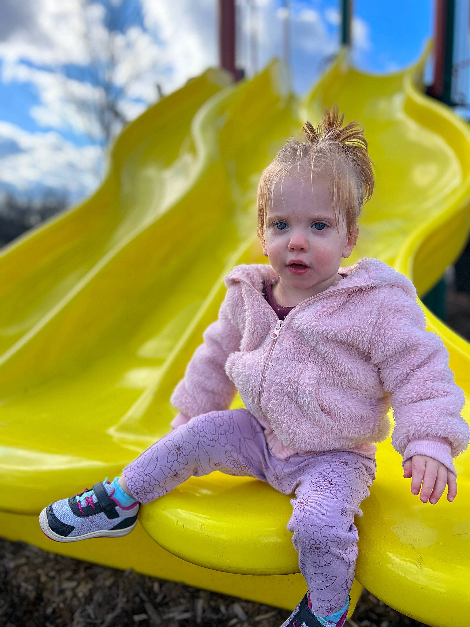 Julie is registered to the contest to win money with this photo: baby, baby_toddler_clothing, child, city, dress, electric_blue, facial_expression, fun, grass, green, happy, leisure, outdoor_play_equipment, people_in_nature, person, playground, public_space, recreation, sitting, toddler