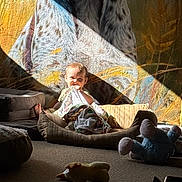 Samuel joined the competition — help win amazing prizes! baby, blanket, cushion, plush_toy, carpet, sunbeam, shadow, tapestry, indoor, child, playing, chewing, fabric, soft_toys, floor, light, cozy, relaxed, resting, home