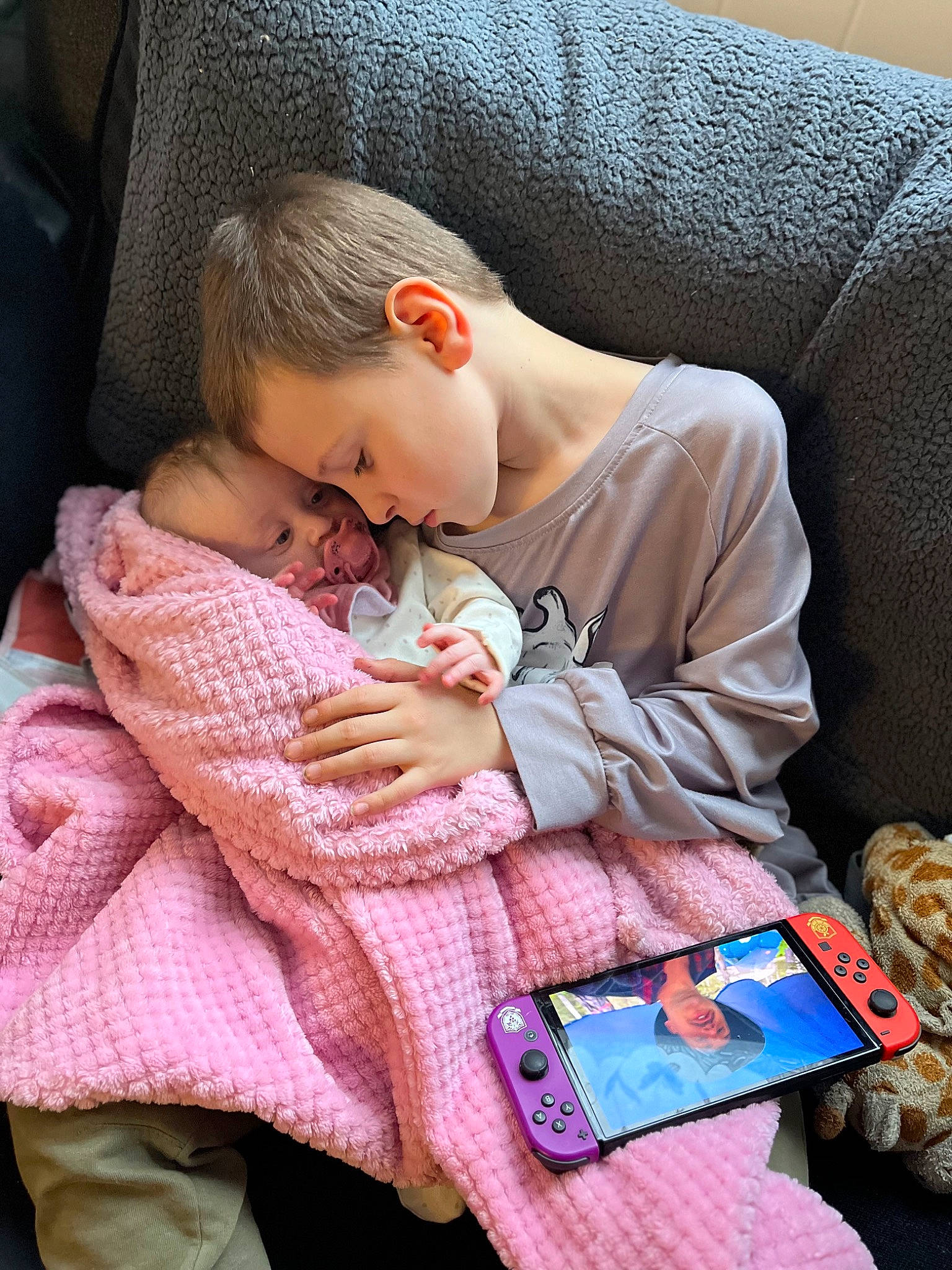 Keegan is registered to the contest to win money with this photo: baby, baby_products, baby_toddler_clothing, car_seat, child, comfort, communication_device, couch, eyewear, finger, human, lap, mobile_phone, nail, person, product, sitting, skin, textile, toddler