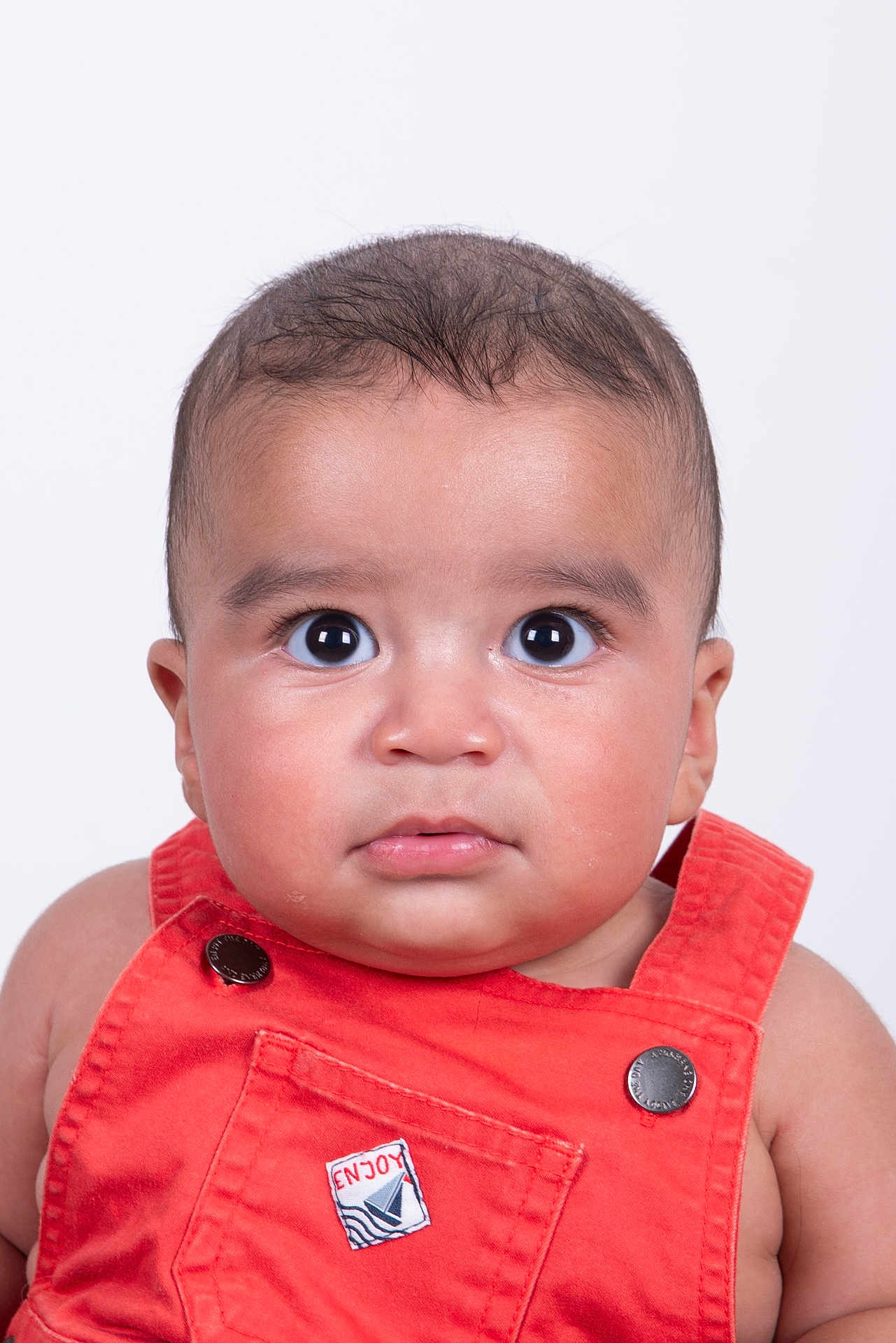 Kassim participe au concours pour gagner de l'argent avec cette photo : baby, child, face, portrait, orange_overalls, clothing, cute, eyes, expression, skin, head, infant, studio, photography, young, adorable, front_view, isolated, white_background, person