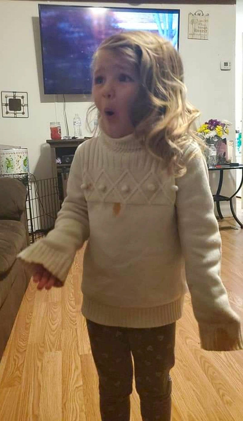 Gracie joined the competition — help win amazing prizes! beige, blond, child, floor, hair, joint, long_hair, neck, outerwear, person, room, shoulder, sleeve, smile, standing, surprise, sweater, top