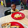 toddler, child, indoor, restaurant, food, pasta, pizza, plate, table, chair, person, hair, curious, casual, dining, floor, cabinet, colorful, meal, seated