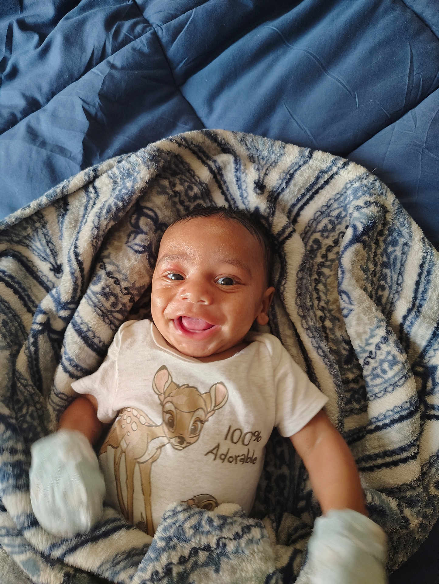 Aubrey joined the competition — help win amazing prizes! baby, infant, smiling, blanket, patterned_blanket, bedspread, clothing, onesie, cartoon, deer, cute, happy, portrait, child, indoor, young_child, mittens, lying_down, cozy, adorable