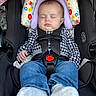 baby, sleeping, car_seat, safety_harness, checkered_shirt, jeans, socks, headrest, floral_pattern, infant, child, seatbelt, resting, indoor, cute, comfort, peaceful, portrait, young_child, clothing