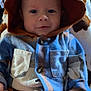 Braxton is registered to the contest to win money with this photo: baby, child, hood, jacket, clothing, blue, brown, blanket, pattern, sitting, hand, face, eyes, infant, cute, indoor, portrait, smile, warm, cozy