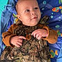 baby, child, camouflage, overalls, pointing, play_mat, toy, colorful, indoor, infant, carhartt_logo, clothing, person, smiling, cute, face, hands, blue, orange, green