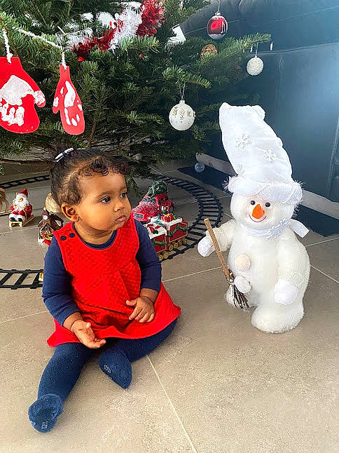 Nora participe au concours pour gagner de l'argent avec cette photo : baby, baby_toddler_clothing, christmas, christmas_decoration, christmas_ornament, christmas_tree, conifer, event, fun, happy, head, holiday, holiday_ornament, ornament, person, plant, tail, toddler, toy, vertebrate