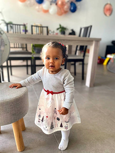 Nora a rejoint le concours — aidez-le/la à gagner de superbes lots ! baby, baby_toddler_clothing, balloon, bookcase, chair, child, dress, event, flooring, fun, furniture, happy, mechanical_fan, person, room, sitting, sleeve, standing, toddler, white