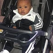 Kyshaun is registered to the contest to win money with this photo: baby, child, stroller, chicco, bravo, tracksuit, sportswear, shoes, white, black, sitting, indoor, carpet, footwear, person, portrait, young_child, cute, expression, seat