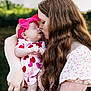 Arya is registered to the contest to win money with this photo: baby, woman, kiss, love, affection, outdoor, nature, headband, pink, red, dress, sleeping, holding, portrait, mother, child, long_hair, freckles, closeup, tenderness