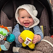 Zayvien is registered to the contest to win money with this photo: baby, infant, stroller, car_seat, toy, plush_toy, stuffed_animal, smile, happy, hood, blue_outfit, seatbelt, shopping_cart, supermarket, portrait, closeup, cheerful, yellow_toy, sock_monkey, hand