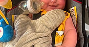 Peyton is registered to the contest to win money with this photo: baby, infant, child, smiling, portrait, car_seat, bottle, blanket, plush_toy, elephant_toy, yellow_clothing, cozy, sitting, indoors, face, hands, legs, baby_gear, happy, photography