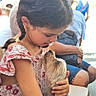 child, dog, braids, love, outdoor, people, seated, casual_clothing, affection, pet, portrait, summer, sunlight, human, animal, cute, holding, interaction, friendship, background