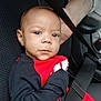 Carson is registered to the contest to win money with this photo: baby, child, car_seat, seatbelt, red_clothing, black_clothing, hand, adult, face, eyes, portrait, car_interior, safety, serious_expression, person, infant, clothing, seatbelt_strap, support, closeup
