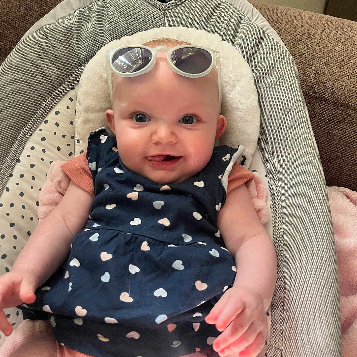 Raphaëlla participe au concours pour gagner de l'argent avec cette photo : baby, baby_seat, child, clothing, cute, fabric, hand, happy, head, heart_pattern, indoor, infant, person, pink_blanket, portrait, seat, skin, smiling, sunglasses, young_child