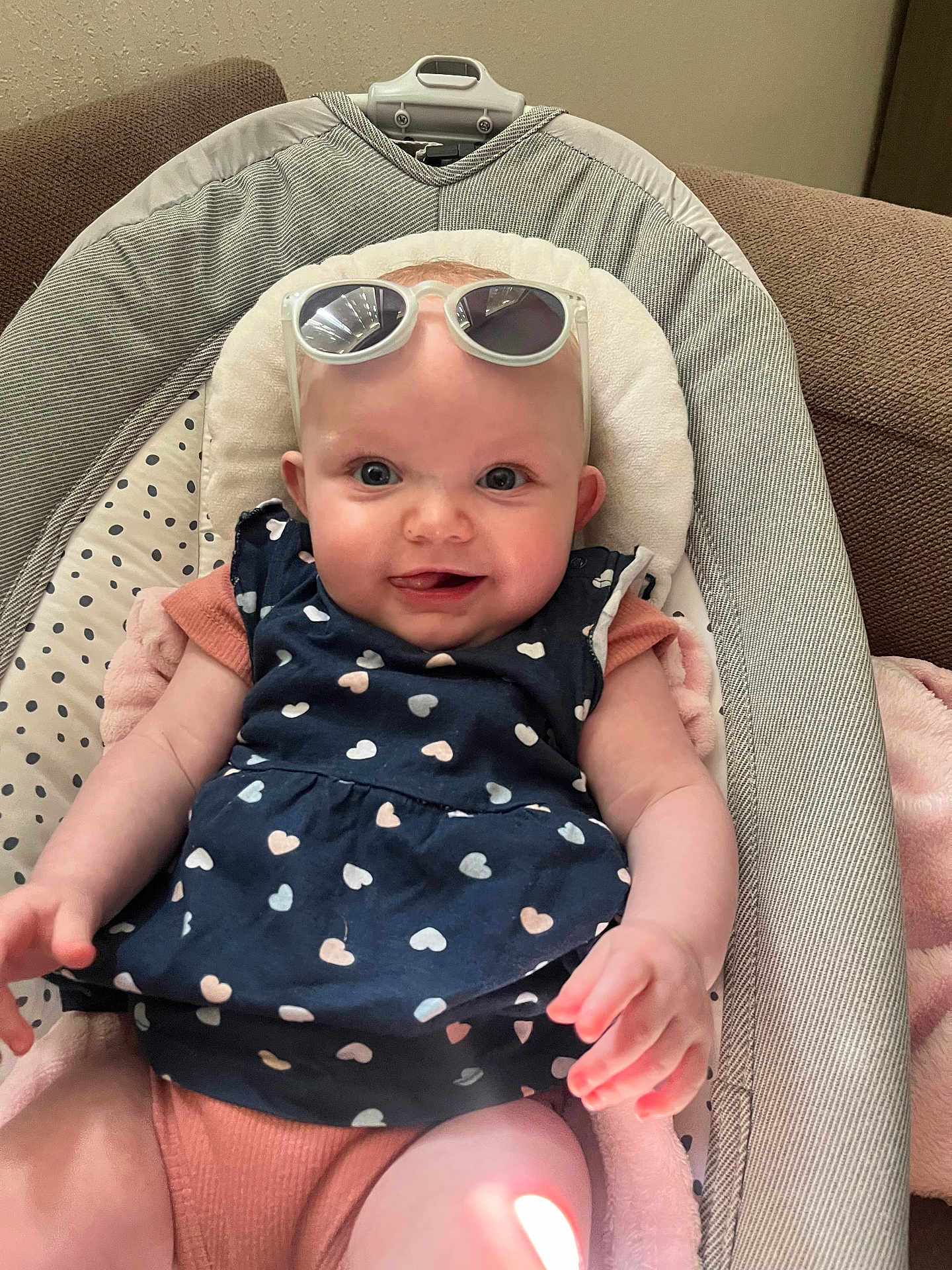 Raphaëlla participe au concours pour gagner de l'argent avec cette photo : baby, infant, smiling, sunglasses, heart_pattern, clothing, seat, baby_seat, indoor, cute, child, person, young_child, pink_blanket, fabric, happy, portrait, skin, hand, head