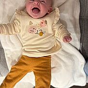 Louna participe au concours pour gagner de l'argent avec cette photo : baby, infant, child, cute, tongue_out, clothing, pants, sweater, blanket, fabric, smiling, happy, lying_down, indoors, cozy, playful, person, face, head, skin