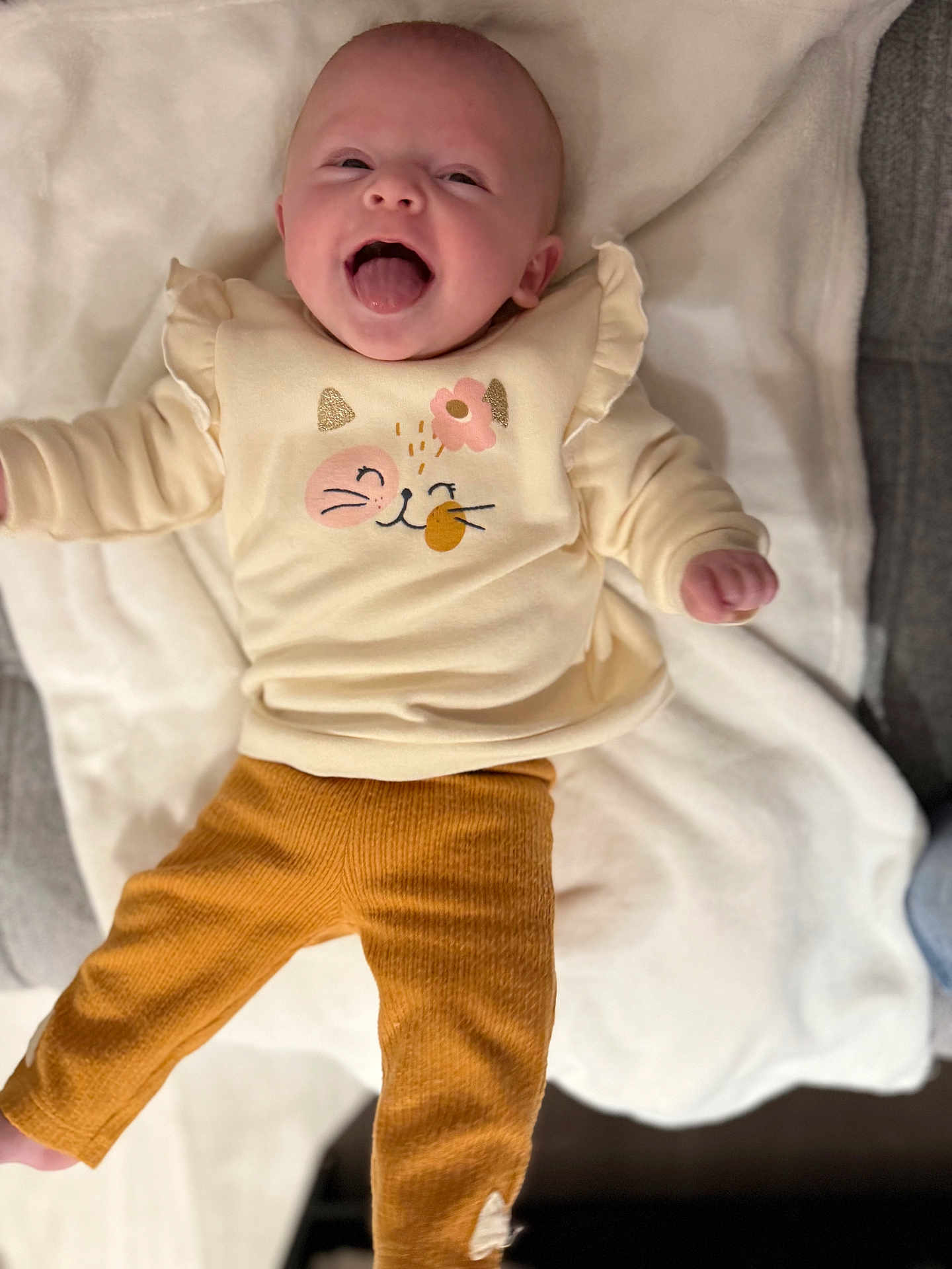 Louna participe au concours pour gagner de l'argent avec cette photo : baby, infant, child, cute, tongue_out, clothing, pants, sweater, blanket, fabric, smiling, happy, lying_down, indoors, cozy, playful, person, face, head, skin