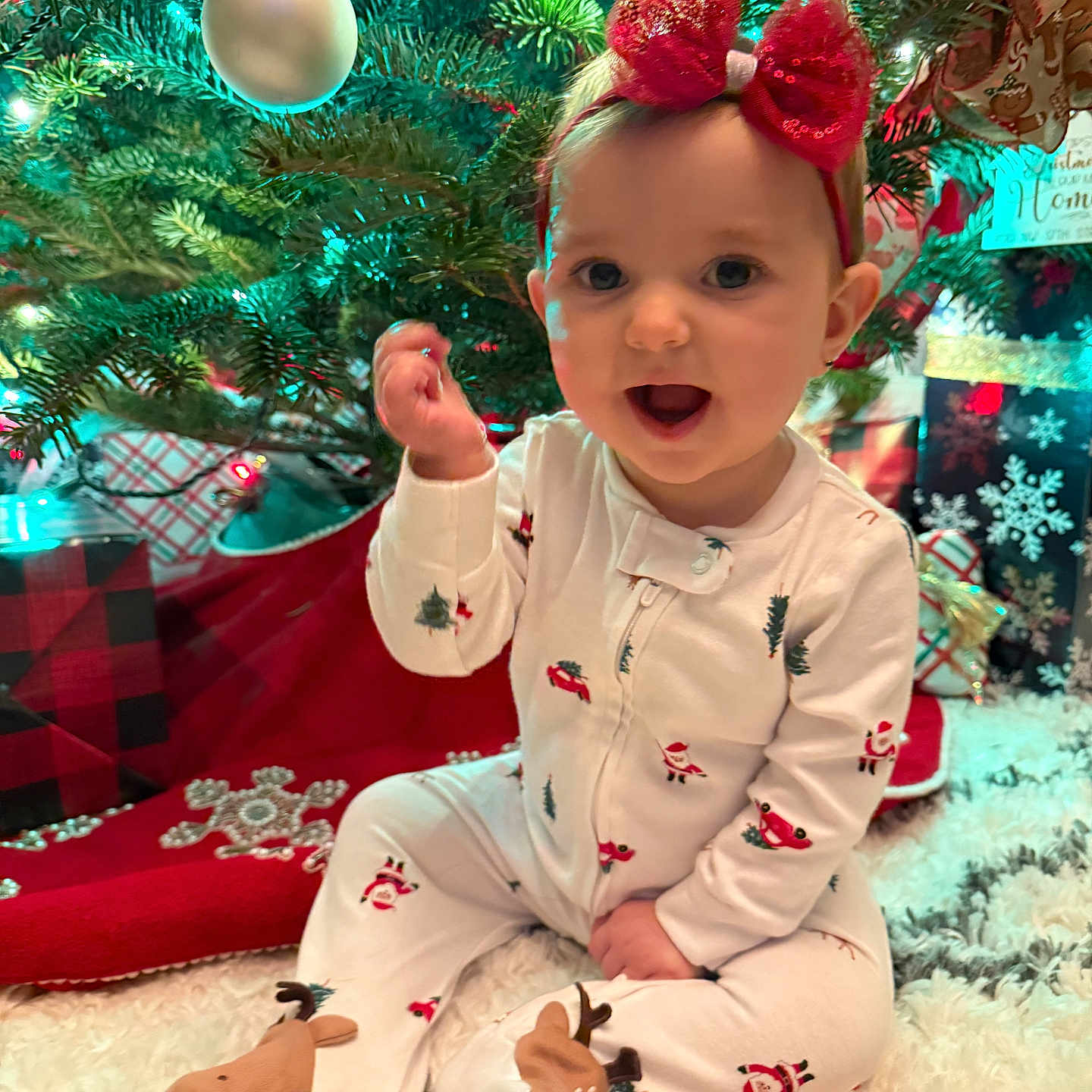 Madelyn joined the competition — help win amazing prizes! baby, carpet, celebration, child, christmas_tree, cute, decorations, festive, happy, headband, holiday, indoors, lights, ornament, pajamas, presents, red_bow, sitting, smiling, winter