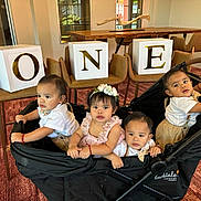 Cuatrillizos joined the competition — help win amazing prizes! toddler, child, stroller, indoor, carpet, wooden_table, chairs, blocks, letters, one, flower_headband, white_shirt, curious, group, people, baby, red_bracelet, expression, caravan_coupe, furniture